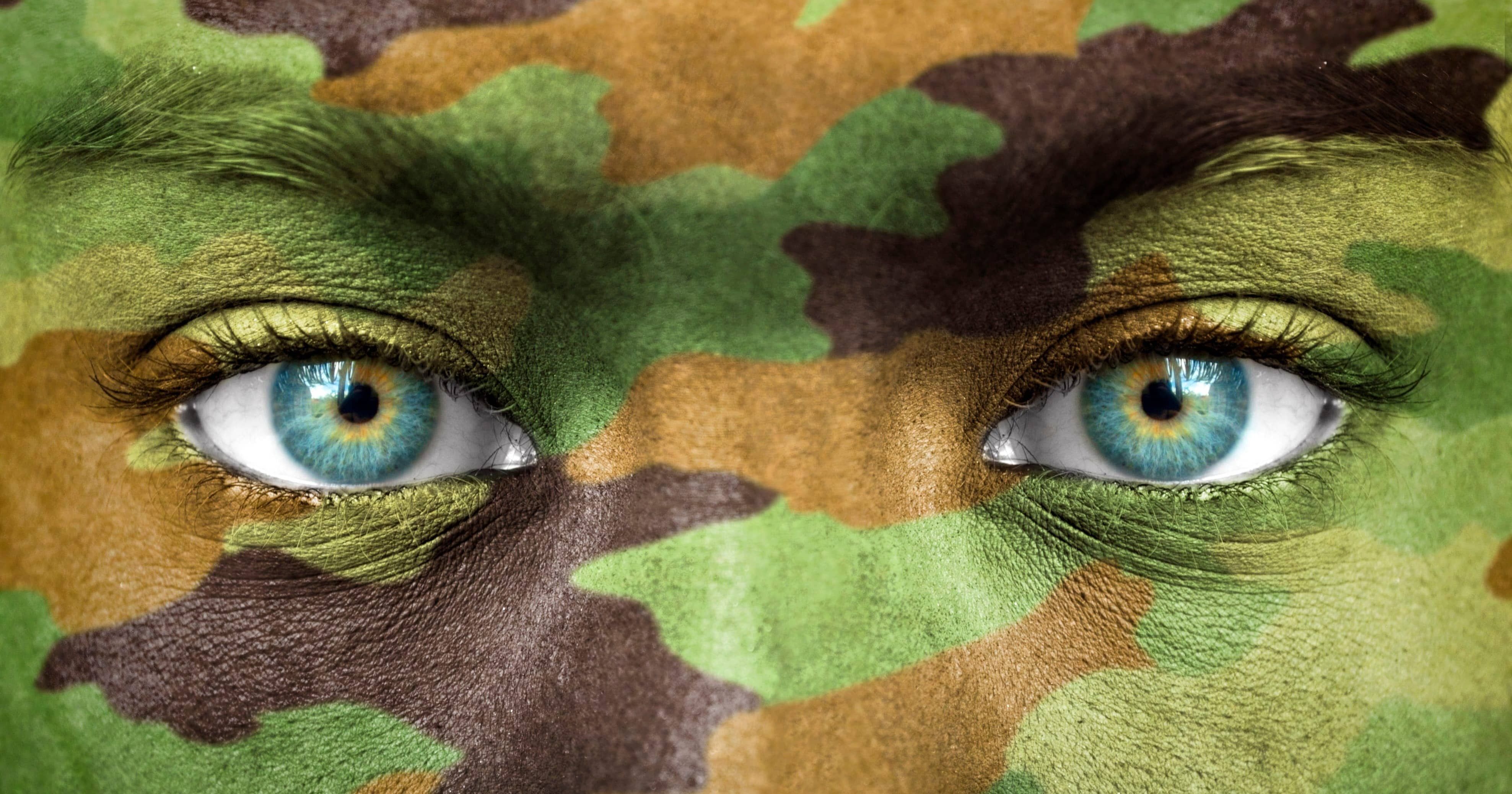 a zoomed in view of a pair of eyes with the face covered in camouflage